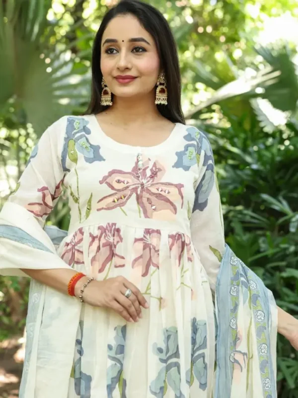 A Graceful Ivory Kurti Set Featuring Soft Pastel Floral Prints, Paired With Matching Pants And A Delicate Blue Dupatta.